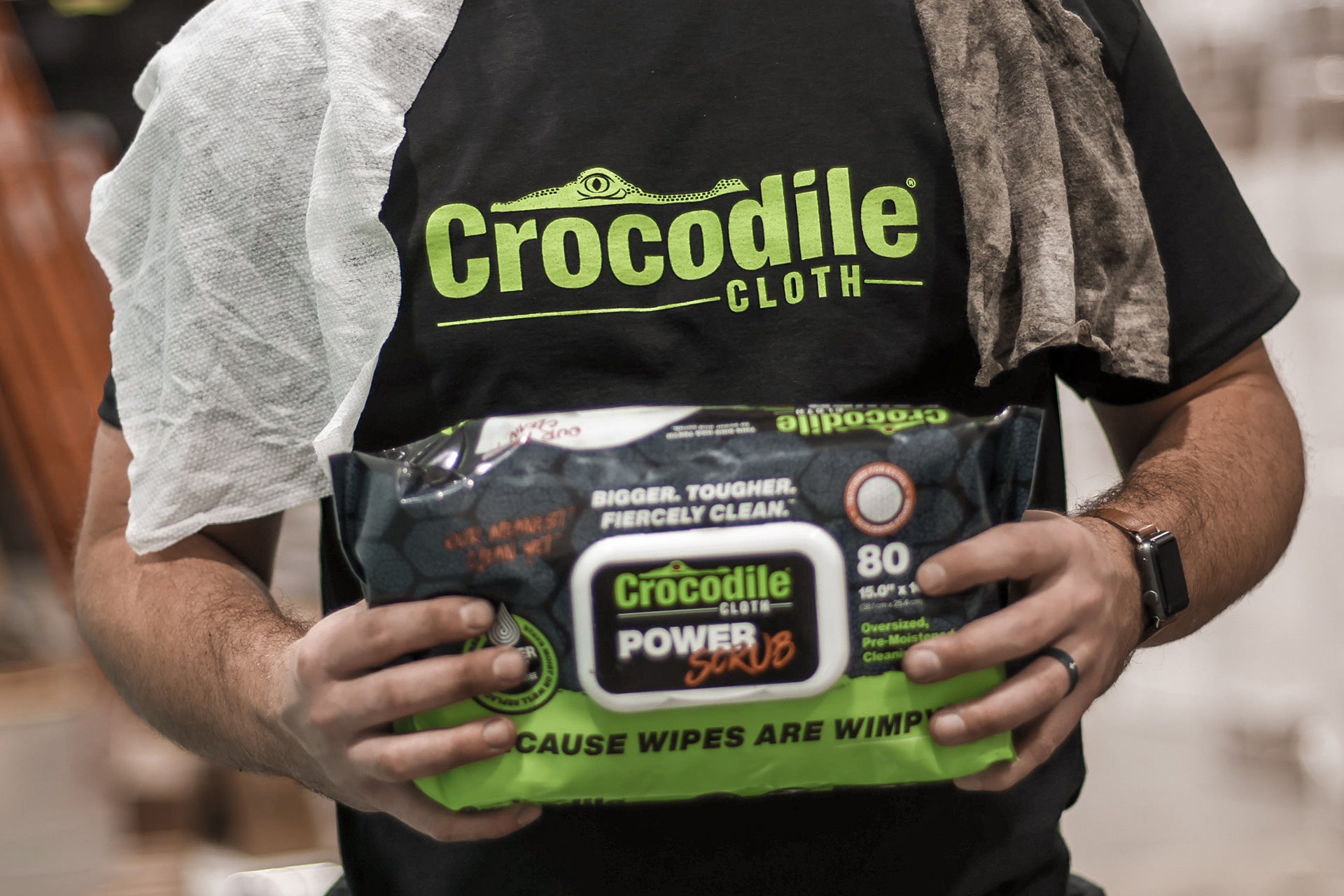 Person holding a package of Crocodile Cloth power wipes with a branded apron.
