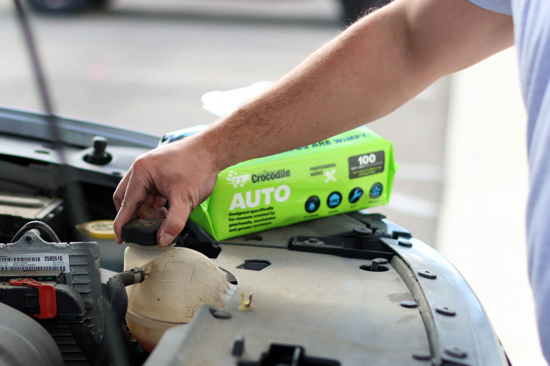 Person working on a vehicle with Crocodile Auto wipes in background