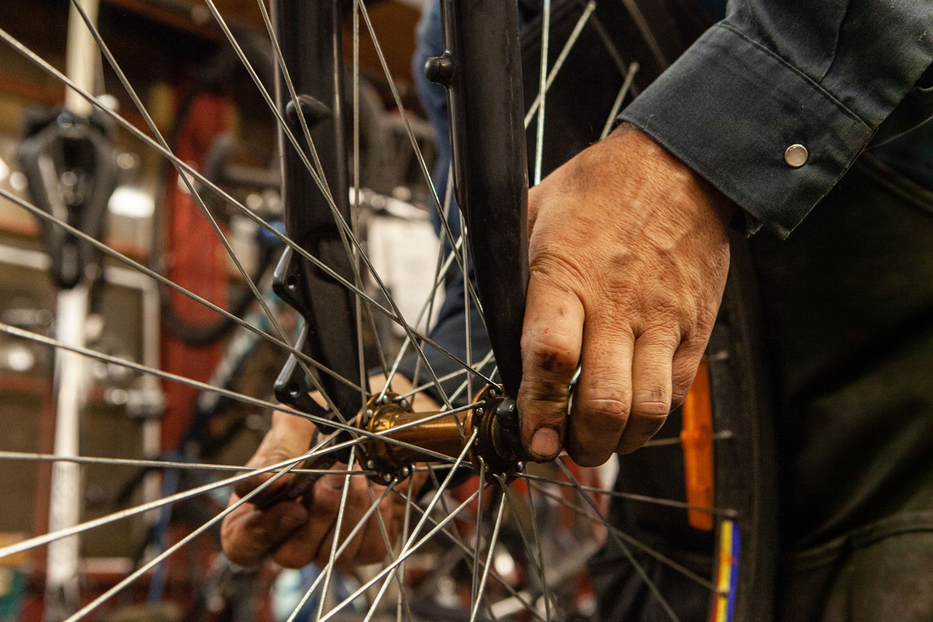 Person working on a bicycle wheel with dirty hands