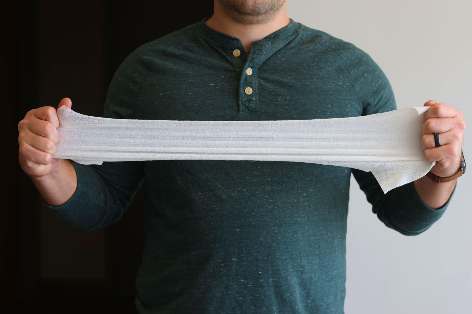 Person holding a stretched out wipe against a neutral background